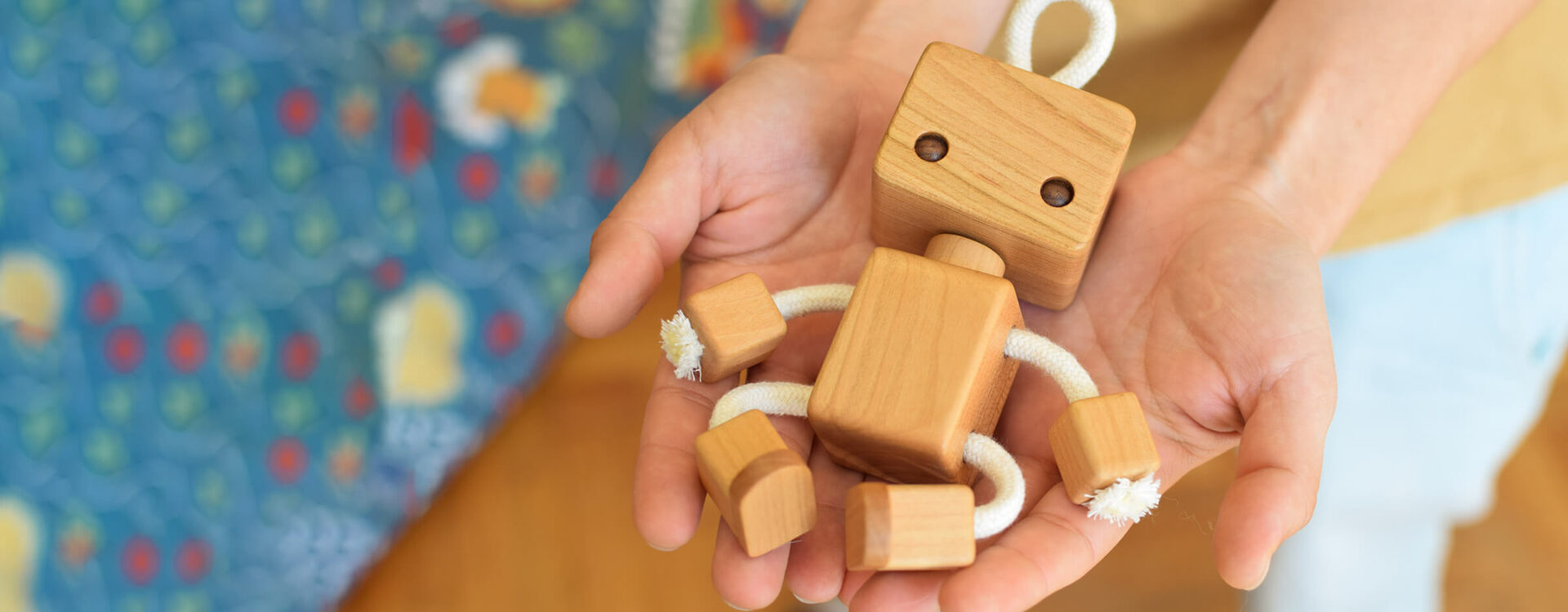 Hands carring wooden robot toy
