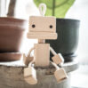 Wooden robot toy sitting by the flowerpots