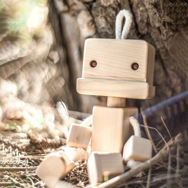 Wooden robot toy sitting by a tree