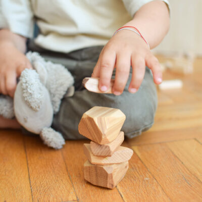 kid building tower of wooden stones