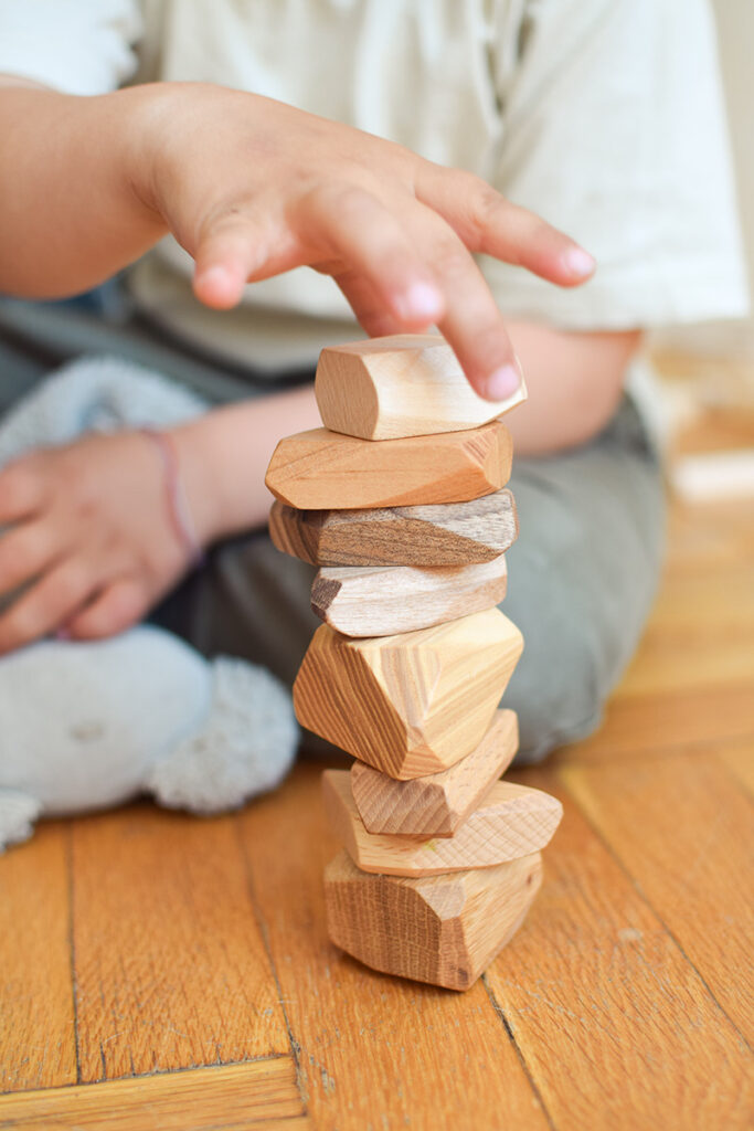 kid building tower of wooden blocks