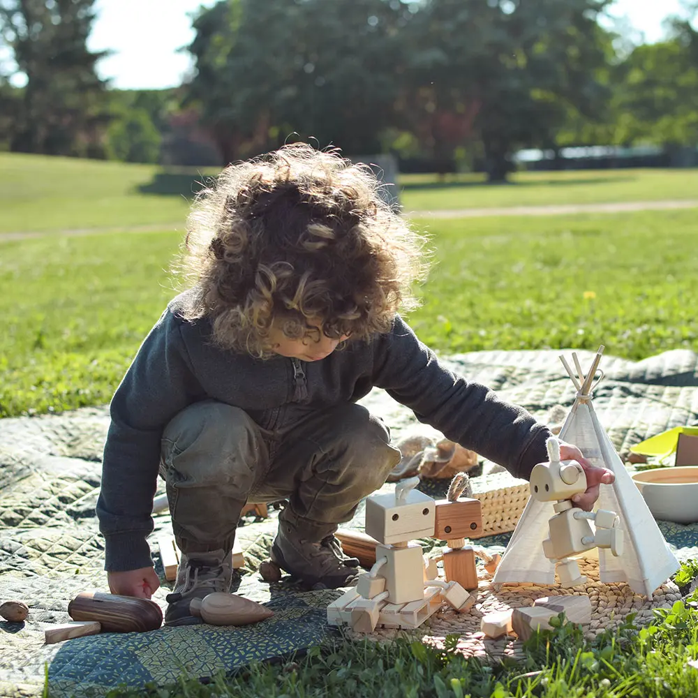 kid playing open ended game with handmade wooden toys