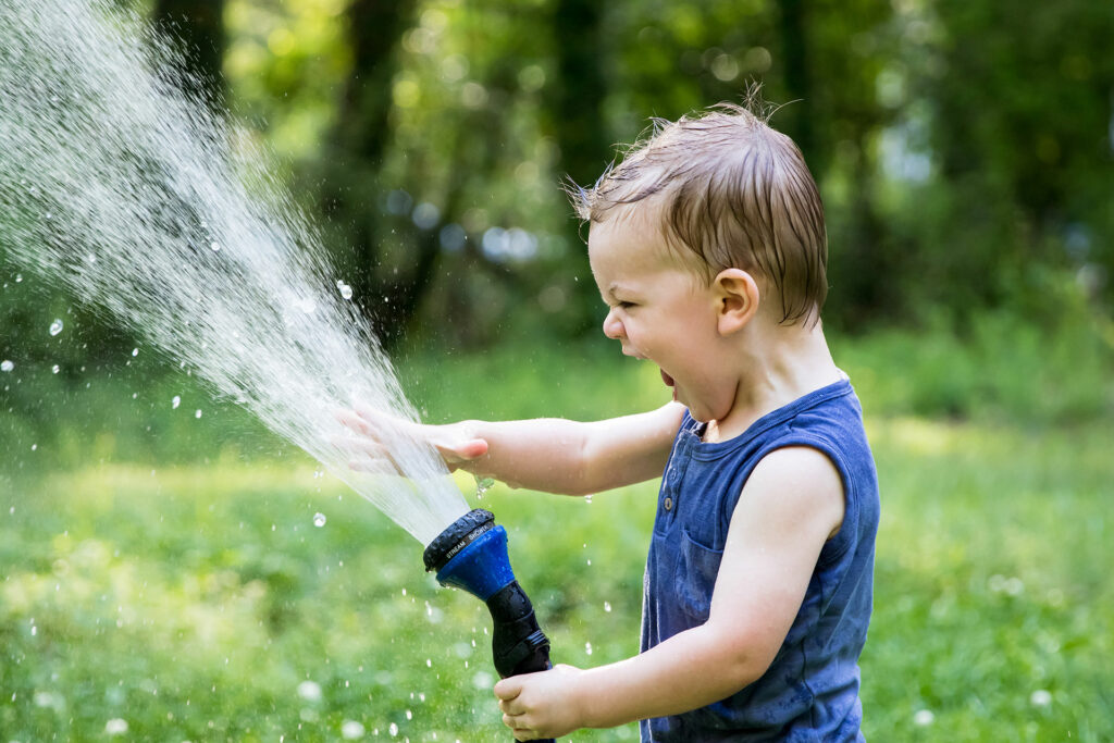 kid enjoing water hose